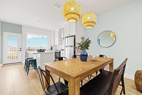 A closer look at the stunning wooden herringbone dining table, beautifully complemented by oversized woven pendant lights that cast a warm, designer glow over every meal