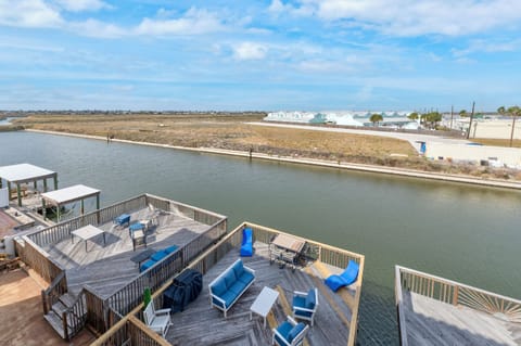 Waterfront deck with blue seating overlooks calm canal waters, offering peaceful views of the surrounding coastal community.