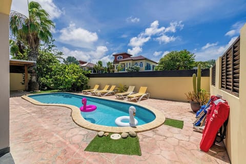Your private poolside retreat awaits with sunny loungers, playful floaties, and a backdrop of tropical palms—perfect for lazy afternoons under blue Caribbean skies.