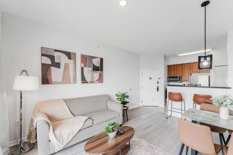 Enjoy a bright and airy living area featuring a cozy sofa and modern artwork, seamlessly flowing into a warm dining space with rich wood tones that creates a welcoming atmosphere for all guests.