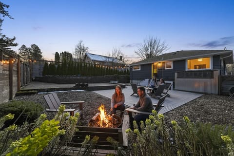 Cozy fenced backyard with fire pit, deck lounge & string lights
