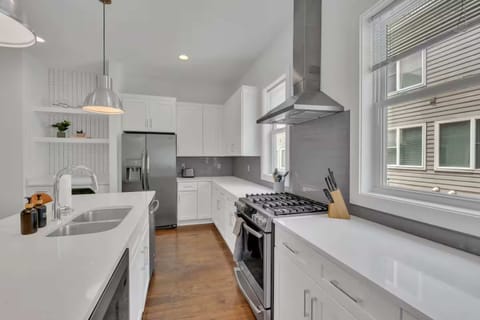 Open-concept kitchen with quartz counters, gas range, and stainless appliances. | Unit B