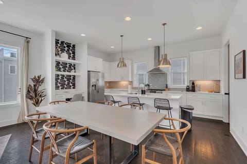 Bright dining and chef’s kitchen with island seating, pendant lights, and coffee bar. | Unit A
