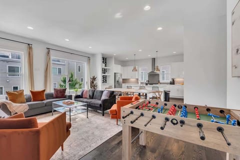 Open-concept living room with plush seating, large windows, and a chef's kitchen. | Unit A