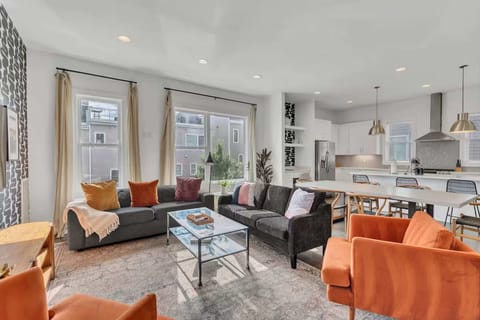 Open-concept living room with foosball table, plush seating, and a bright, modern kitchen. | Unit A