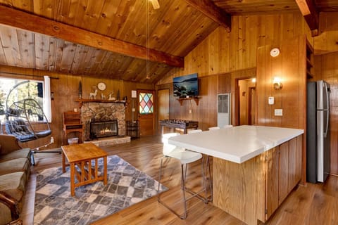 Cozy mountain living room with a stone fireplace, comfy seating, and smart TV—perfect for relaxing evenings, movie nights, and warm cabin vibes after outdoor adventures.