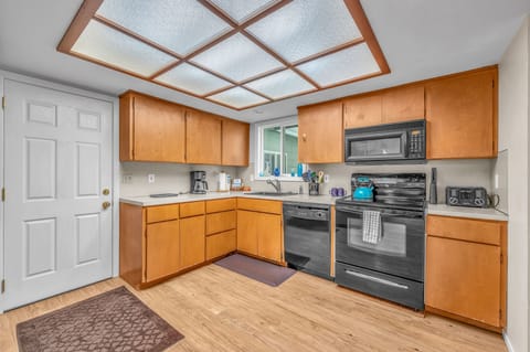 Your fully equipped kitchen awaits with warm wood cabinets, stainless appliances, and a stunning skylight ceiling that bathes your cooking space in natural light.