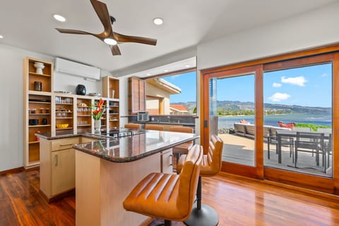 Stunning ocean views through floor-to-ceiling windows while enjoying your modern kitchen's granite counters and open shelving.