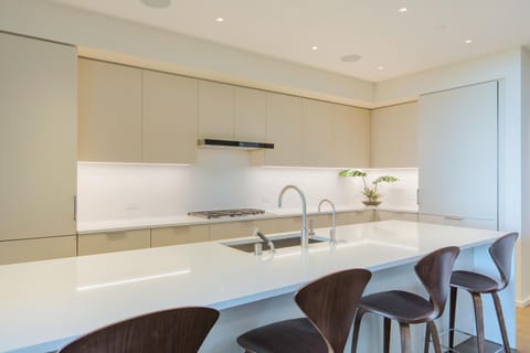 Your sleek gourmet kitchen features pristine white quartz counters, modern bar seating, and professional-grade appliances for memorable meals.