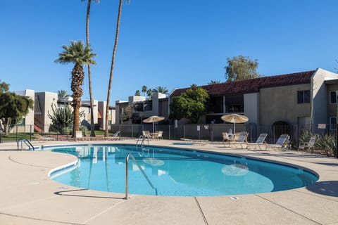 Sparkling blue heated community pool with comfortable loungers under desert sunshine.