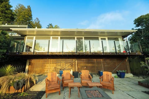 Enjoy outdoor living at its finest with this spacious patio featuring comfortable seating, surrounded by greenery and set beneath a beautifully designed modern home with expansive windows