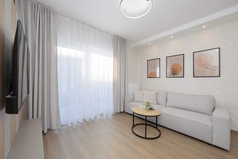 Bright living room with soft textiles, wall art, and natural light flowing through sheer curtains.