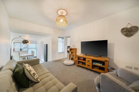 Bright open-plan living room with large TV and comfortable seating