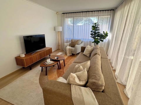 Relax in this bright, open-plan living area featuring a large, cozy sofa, a wide-screen TV for movie nights