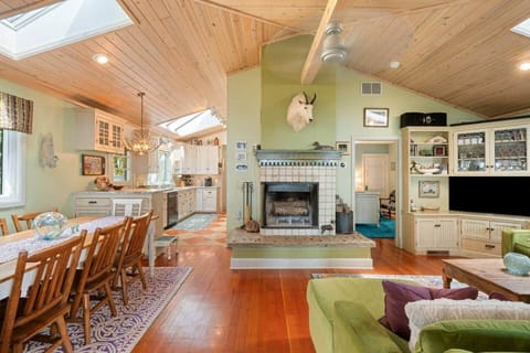 Spacious, skylit living room with warm wood ceilings, plush green sectional, and charming personal touches—perfect for relaxing or gathering with loved ones.