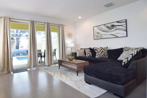 Beautiful lounge area with L-shaped sofa, 75-inch Smart TV, doors to pool deck