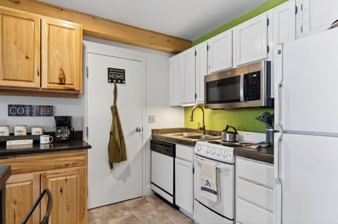 Fully equipped kitchen with white appliances and a green accent wall.