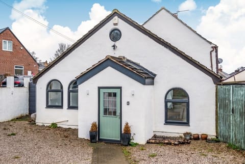 Charming white cottage with arched windows and a welcoming sage front door.