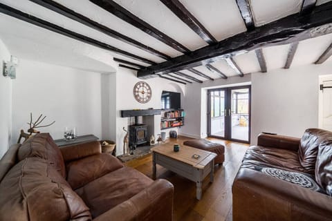 Living room with exposed ceiling beams, leather sofas, and a central coffee table.