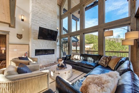 Relax in your spacious living room with soaring ceilings, cozy fireplace, and stunning mountain views through floor-to-ceiling windows.