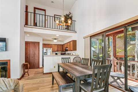 Gather around your spacious dining table where warm wood tones and soaring ceilings create an inviting atmosphere for memorable meals together.