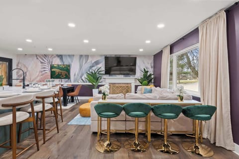 Stylish dining space w/ long table, green barstools & large windows bringing in natural light.