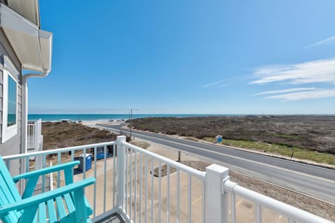 Stunning oceanfront balcony with turquoise chairs where you'll savor morning coffee while watching waves roll in across pristine shores.