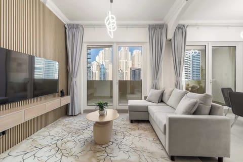 A serene angle of the living room highlights the stylish round coffee tables, the plush grey sofa, and floor-to-ceiling curtains framing the breathtaking Dubai skyline view.