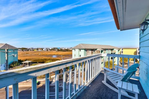 Step onto your private balcony and soak in breathtaking marshland views stretching to colorful coastal homes under endless blue skies.