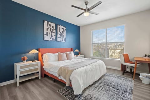 Thoughtfully designed bedroom offering a cozy sleeping area and a dedicated workspace. Large windows fill the room with natural light, making it perfect for both productivity and relaxation during short or extended stays.