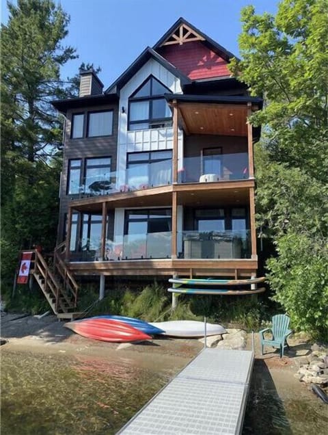 Front of cottage from dock with beach and watercraft