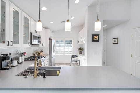 Your bright, modern kitchen features sleek white cabinets, pendant lighting, and spacious countertops perfect for preparing meals together.