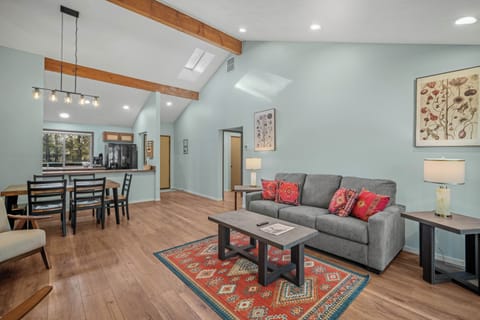 Relax in your open-concept living space featuring soaring ceilings, warm wood beams, and stylish furnishings that create the perfect home away from home.