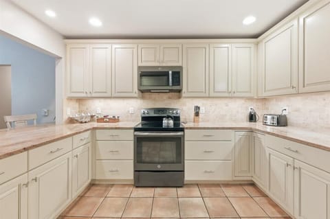 Modern kitchen with granite counters, stainless appliances, and a breakfast bar for three.