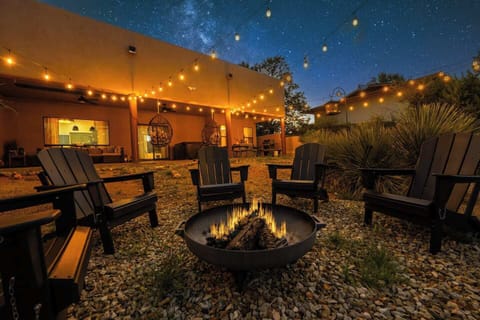 Enchanting outdoor space with a fire pit and Adirondack chairs! Relax under string lights with a starry sky overhead. Hot tub and cozy patio nearby. Ideal for memorable nights!