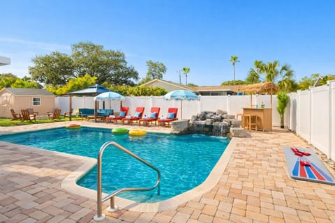 Private pool area with waterfall feature, tiki bar, and outdoor games