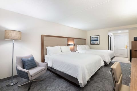 Spacious room with two queen beds, chair seating, and soft lighting