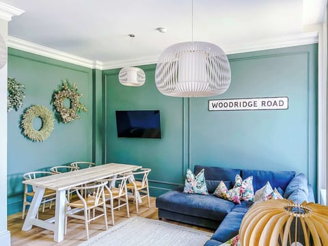 Bright and stylish dining area featuring a spacious wooden table with comfortable seating for family meals or gatherings. Set against elegant green panelled walls with modern lighting, it’s the perfect space to dine, work, or enjoy quality time toget