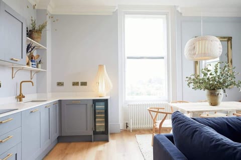 Bright and inviting living room with a navy sofa, large windows, and warm wood floors. Scandinavian-inspired décor blends modern style with comfort, creating a cozy space perfect for relaxing or entertaining in natural light.