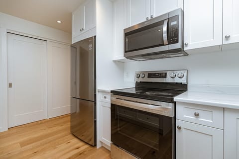 Fully equipped with a stainless steel fridge, electric stove, and built-in microwave