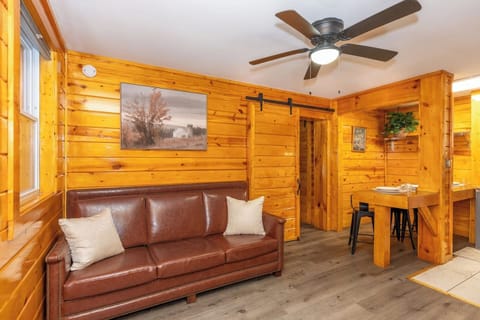 - Cozy log cabin living room with leather sofa and rustic barn door charm - Warm wood interiors, smart TV, ceiling fan and stylish farmhouse decor - Perfect romantic getaway suite near nature trails and downtown dining