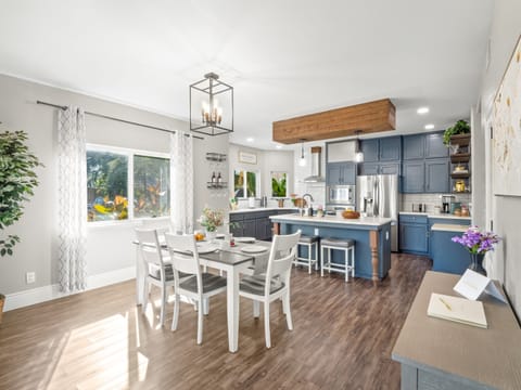 Bright open kitchen and dining area with seating for everyone, a spacious island for casual meals, and a fully equipped kitchen with stainless steel appliances—perfect for cooking, gathering, and making memories together.