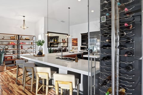 Open kitchen with oversized island, bar seating, and a stylish wine display.