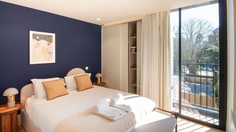 Sophisticated bedroom with bold navy accent wall, direct balcony access, and built-in wardrobe, designed for restful nights and bright mornings.
#BalconyBedroom #PortoDesign #NaturalLight #ModernComfort
