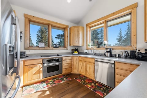 Kitchen: Open-concept layout, breakfast bar seating, stainless steel appliances, and radiant floor heat