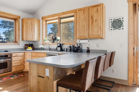 Kitchen: Open-concept layout, breakfast bar seating, stainless steel appliances, and radiant floor heat