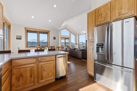 Kitchen: Open-concept layout, breakfast bar seating, stainless steel appliances, and radiant floor heat