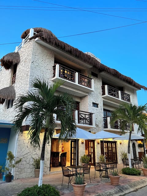Boutique hotel facade featuring local stone walls, dining patio, and palapa roof