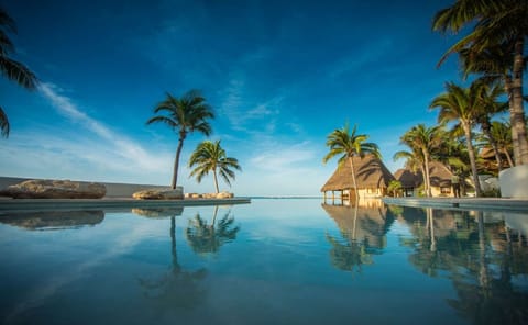 Float at sunset as reflections shimmer across the calm infinity edge.