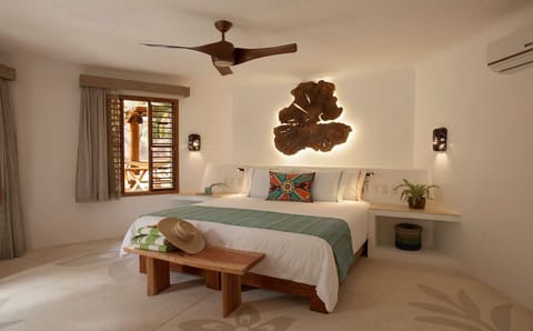 Unwind in crisp linens beneath warm, sculptural wall art.